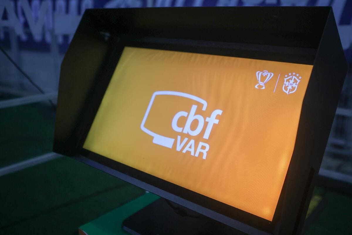 Sistema VAR sendo utilizado em partida de futebol com árbitros analisando lance polêmico